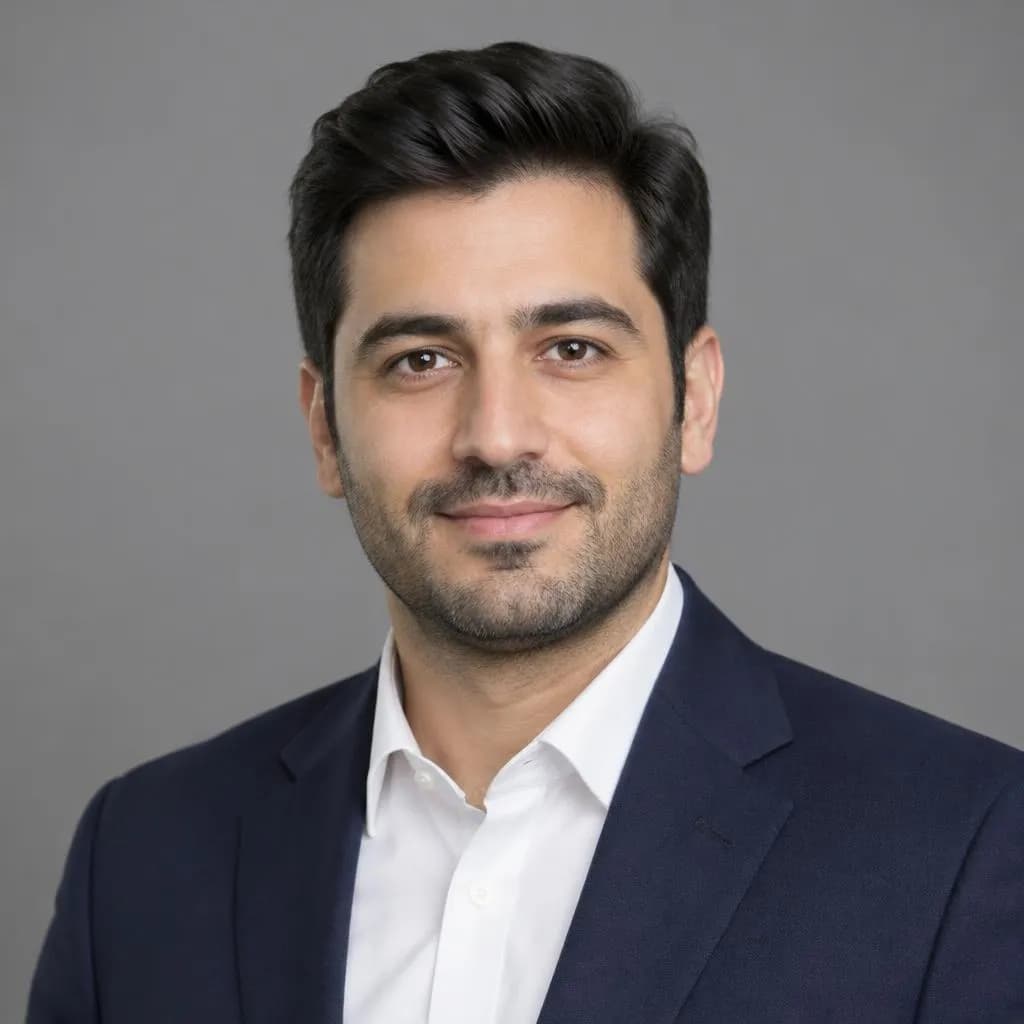 عکس پرسنلی مردی با کت سرمه‌ای و پیراهن سفید روی پس‌زمینهٔ خاکستری ساده